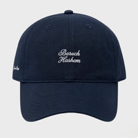 Navy blue cap with 'Baruch Hashem' embroidered on a light gray background
